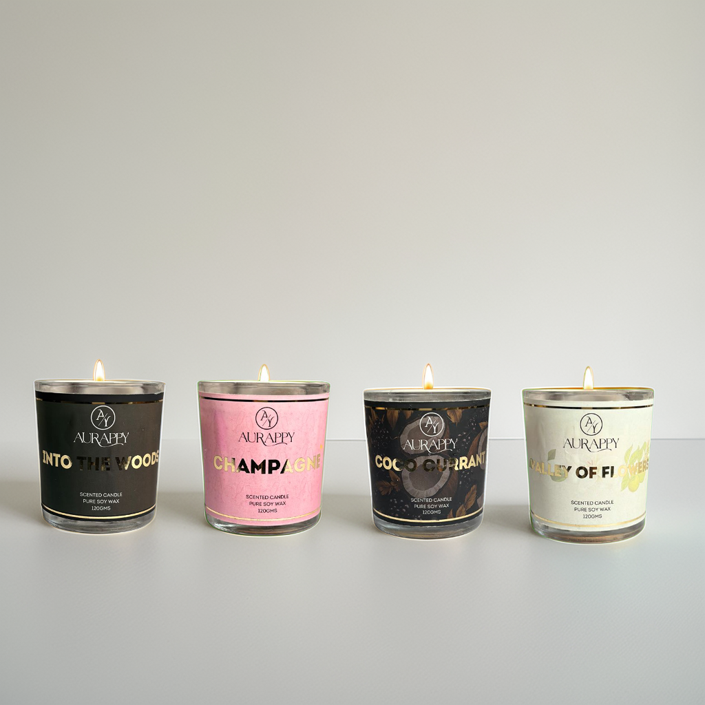 Four lit candles of different scents on a gray background