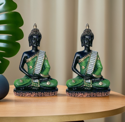 Two ornate Buddha statues with green and black colors on a wooden surface.