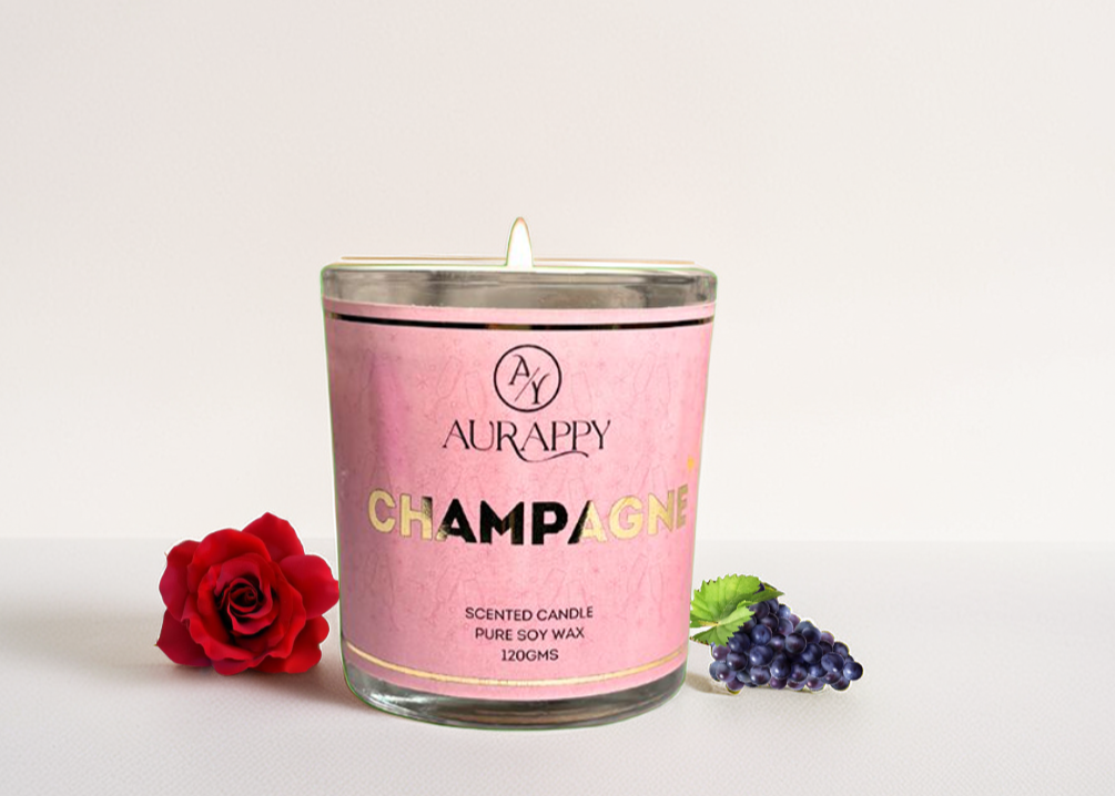 Pink scented candle labeled 'Champagne' by Aurappy with a red rose and purple grapes on a light background