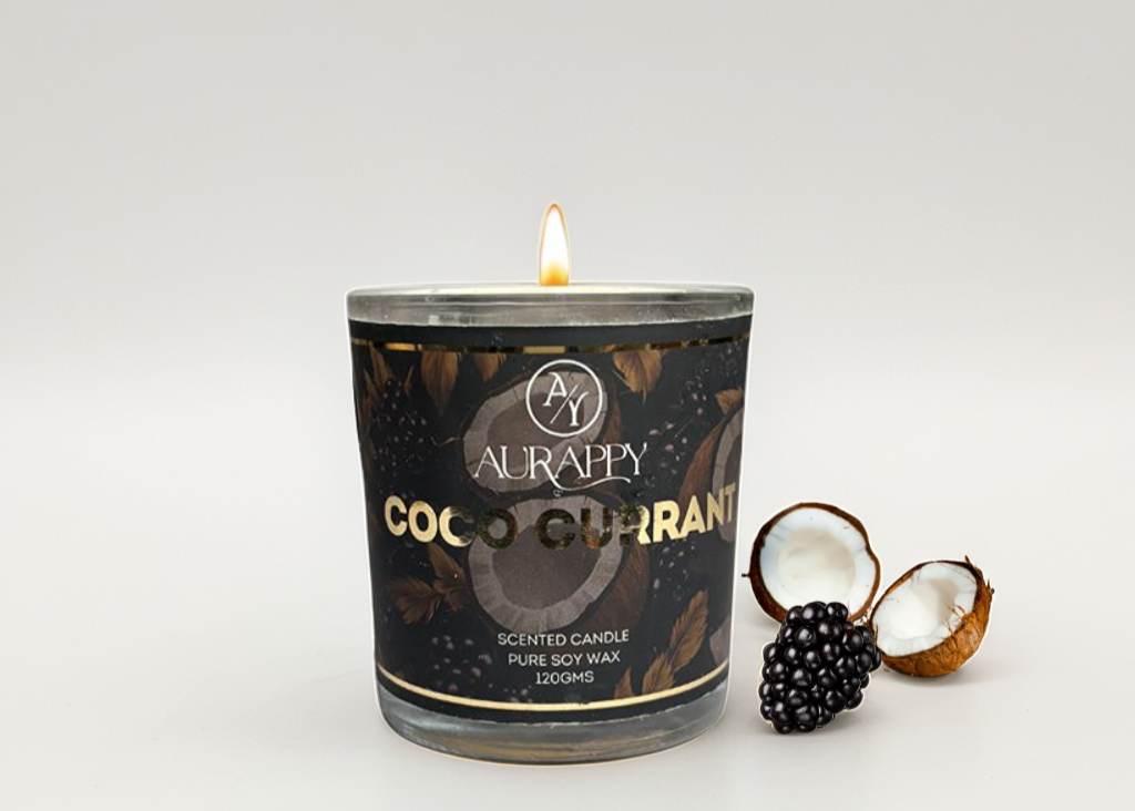 Aurappy Coco Currant candle with a lit wick on a white background with coconut and black currant