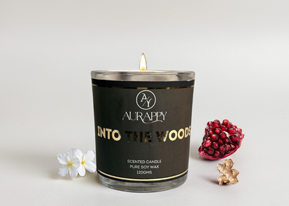 Aurappy candle labeled 'Into The Woods' with pomegranate, jasmine, and ginger elements on a light background