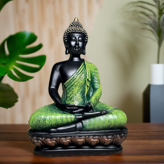 Statue of a meditating Buddha figure with green and black colors on a wooden surface.