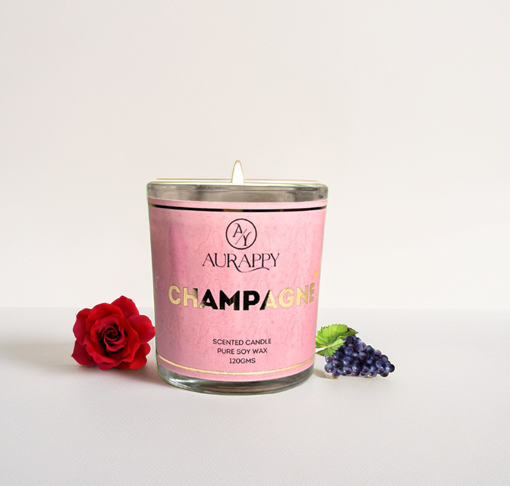 Pink scented candle labeled 'Champagne' by Aurappy with a red rose and purple grapes on a light background