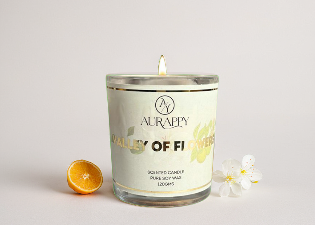 Aurappy Valley of Flowers scented candle with a lighted wick on a white background