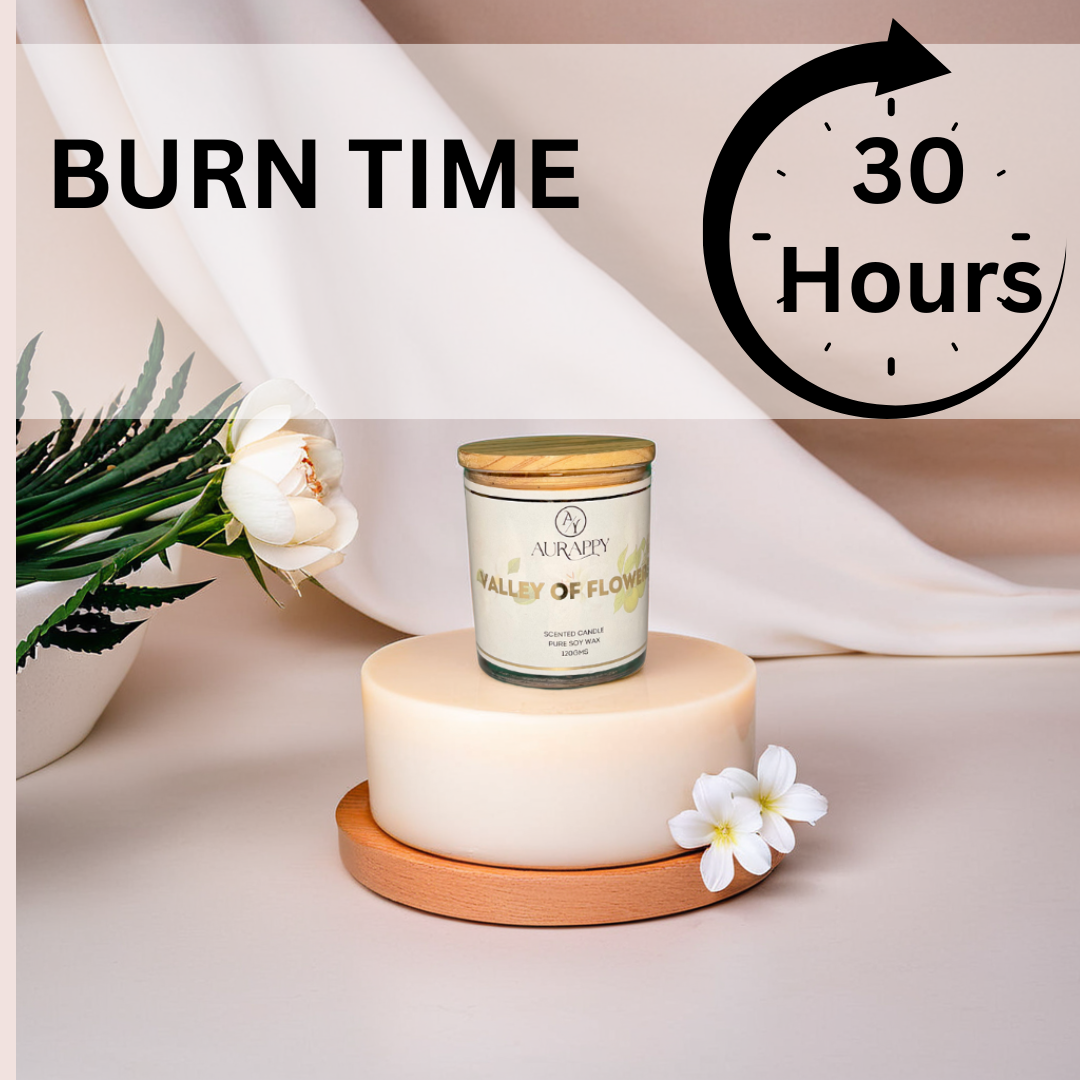 Candle with a wooden lid on a white surface, surrounded by flowers and a plant, with text indicating burn time.