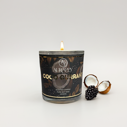 Aurappy Coco Currant candle with a lit wick on a white background with coconut and black currant