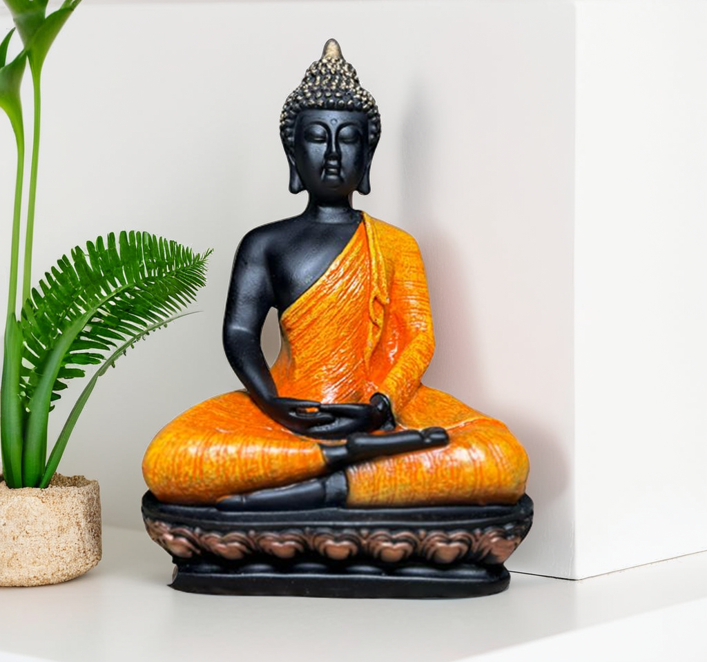 Buddha statue with orange robe and black figure on a white surface with a plant.