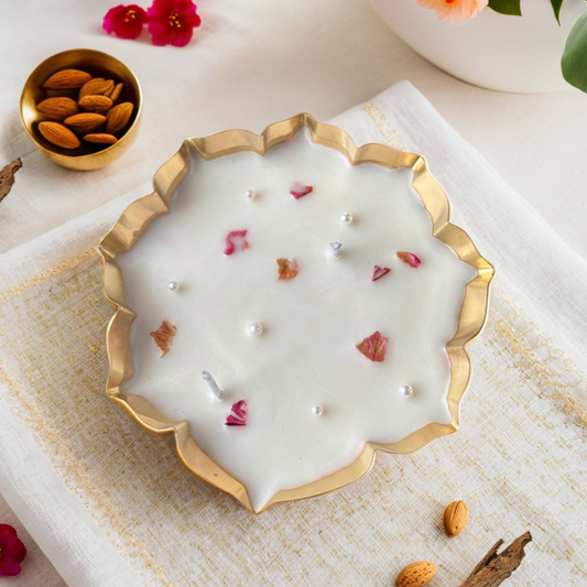 Decorative urli candle with pearls and flowers on a white surface with almonds and flowers.