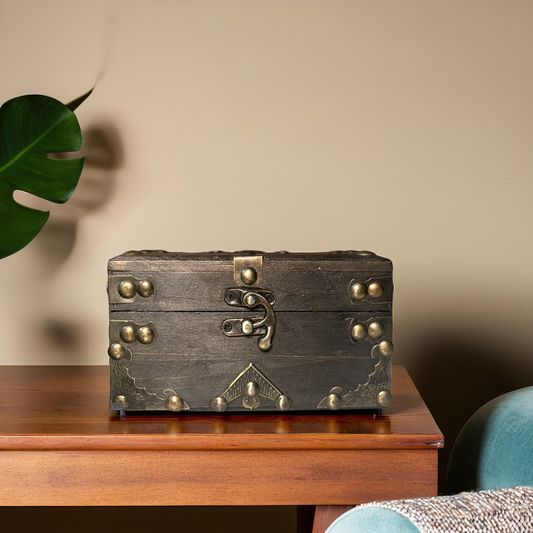 Vintage-style wooden box with brass studs and latch on a wooden surface.